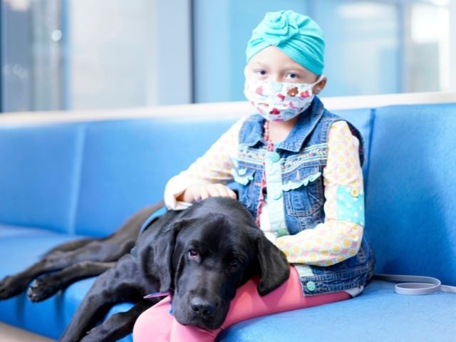 Cancer patient Camille Atkinson with Children's Hospital facility dog Squid